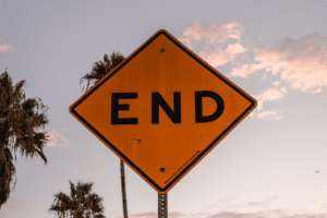 Yellow end sign with palm trees and clouds in the background