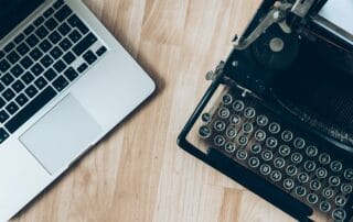 silver laptop angled on the left and black typewriter angled on the right